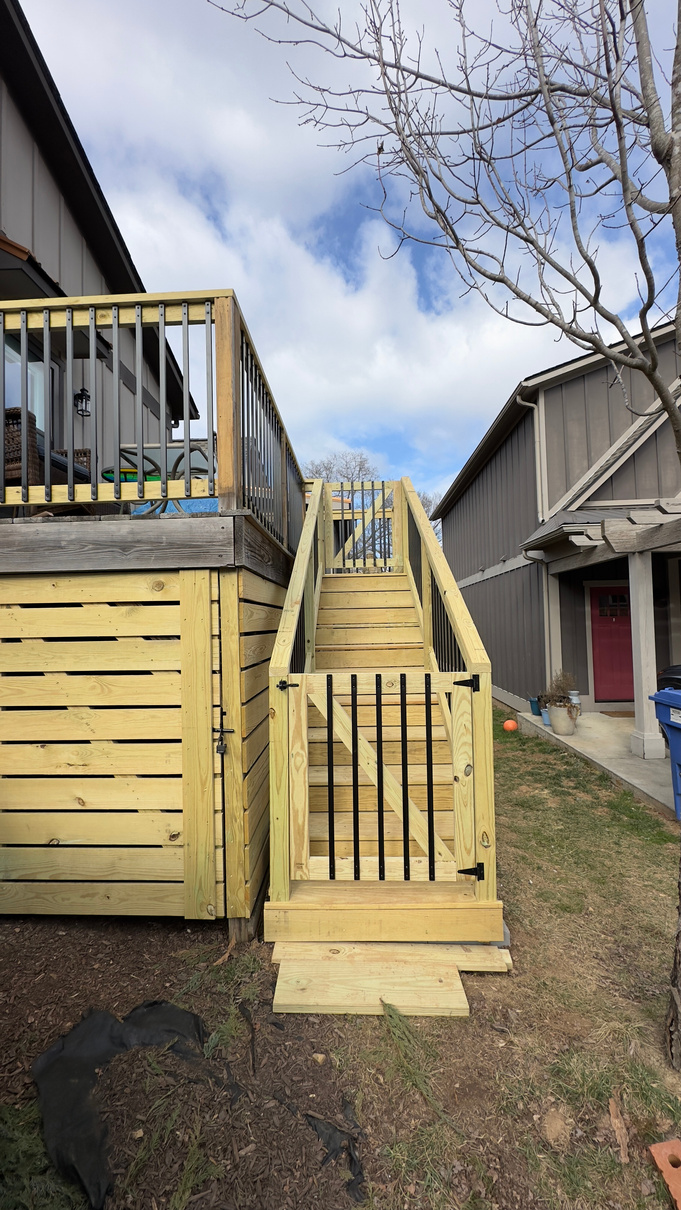 a wooden deck renovation with stairs and gate